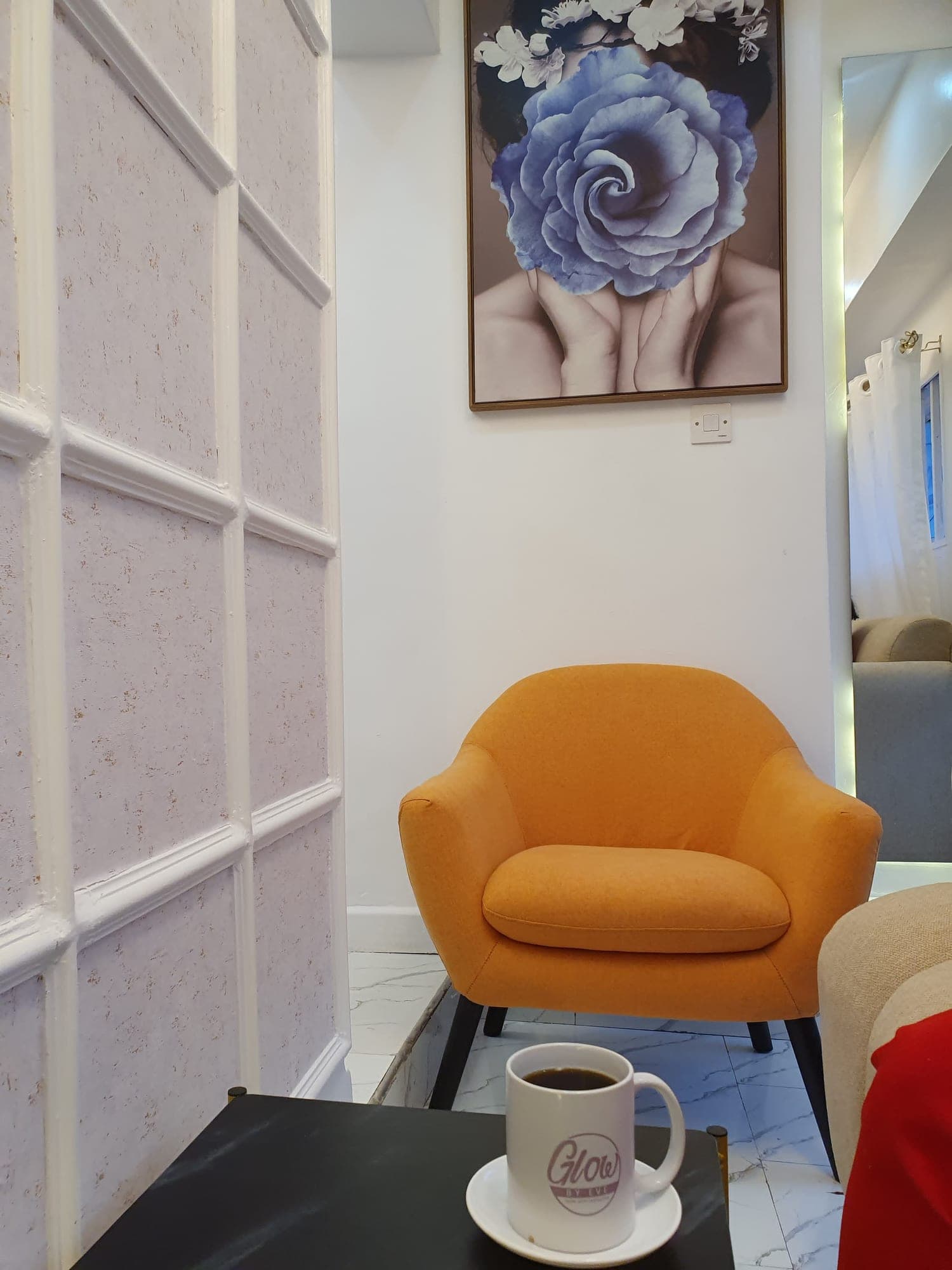 The waiting area at Glow by Eve: an orange armchair, a Glow by Eve mug and framed art.