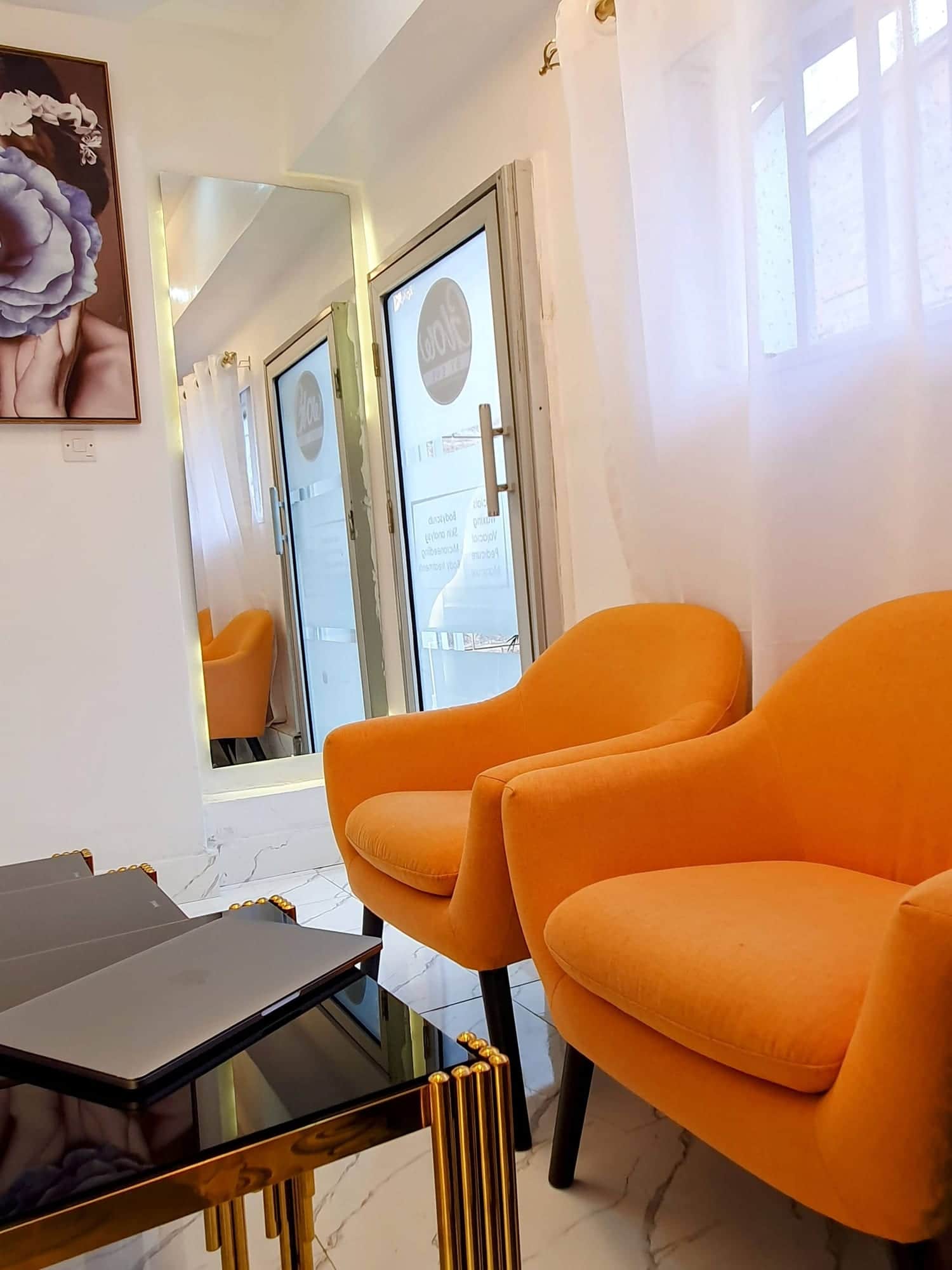 The front of the spa: orange armchairs by the window, a mirror and framed art.